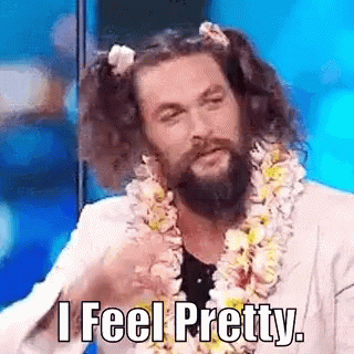Jason Momoa is pink pigtails and a lei tossing hair. (Text) I feel pretty.
