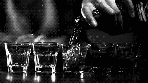 Liquor being poured into shot glasses.